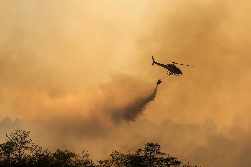 Un hélicoptère de lutte contre les incendies transporte un réservoir d'eau pour éteindre l'incendie de forêt.