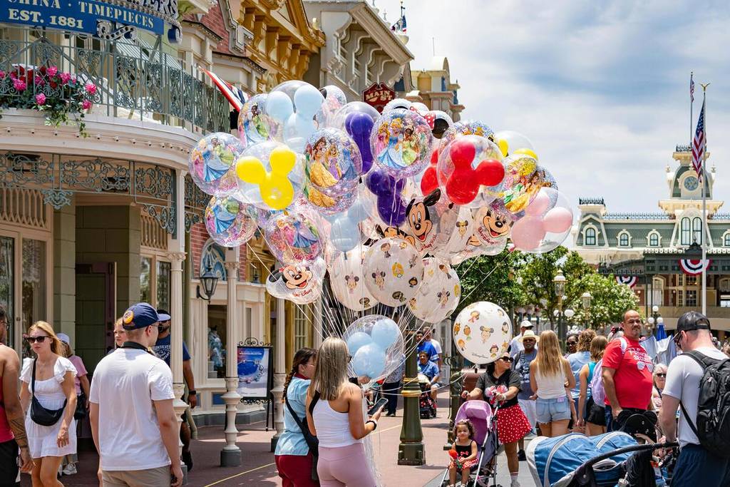 Des ballons colorés sur le thème de Disney sur Main Street, USA à Disney World, avec une foule animée profitant d’une journée ensoleillée