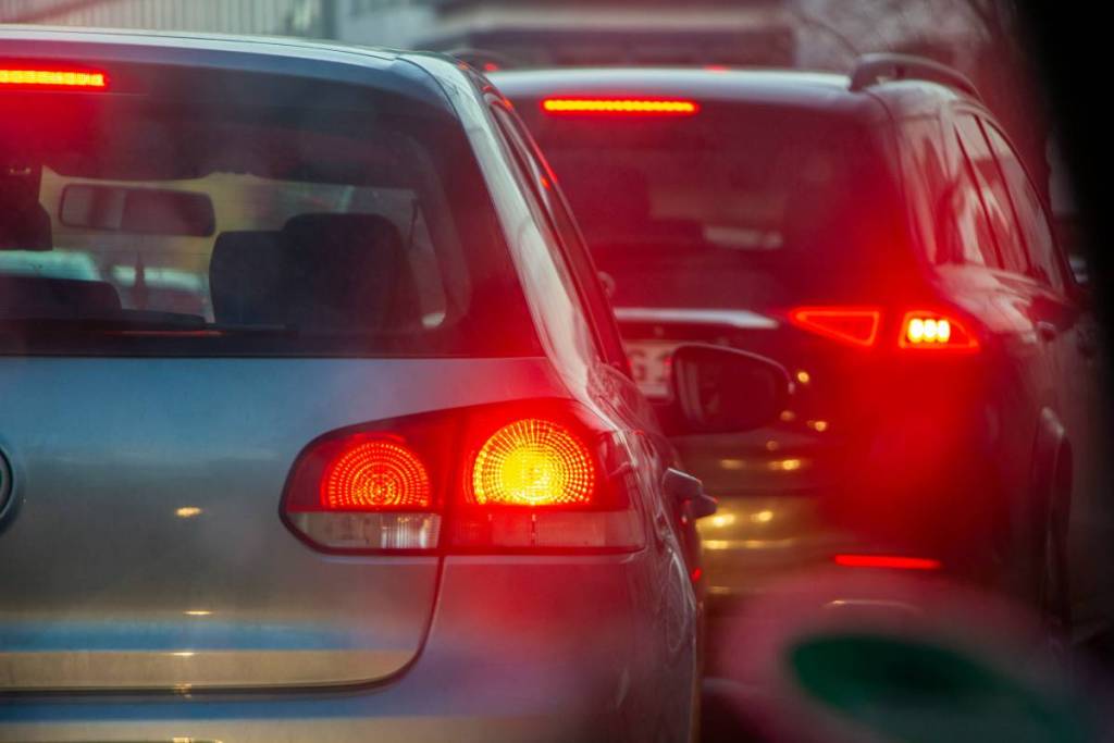 Um grupo de carros circulando numa rua, um ao lado do outro