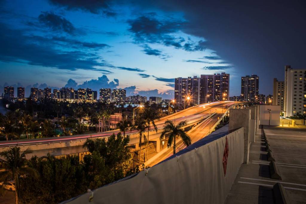 Uma linda vista do horizonte de Miami Beach ao entardecer, com palmeiras e ruas iluminadas.