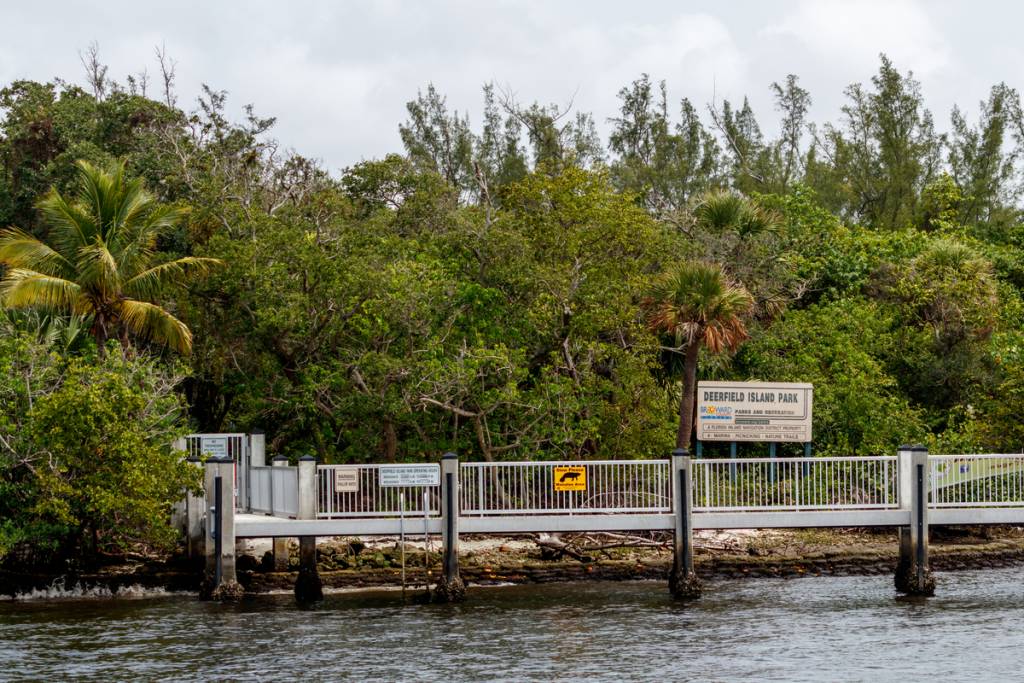 Deerfield Beach, Florida, USA – 19. Juni 2021: Ein aus Metall und Holz gebauter Steg mit einem Manatee-Schild auf Deerfield Island, verwaltet von den Broward County Parks, gegenüber dem Sullivan Park und dem Intercoastal Waterway.