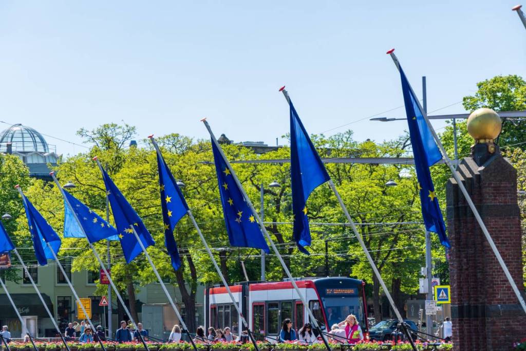 European Union flags displayed prominently in a vibrant city scene with tram and people