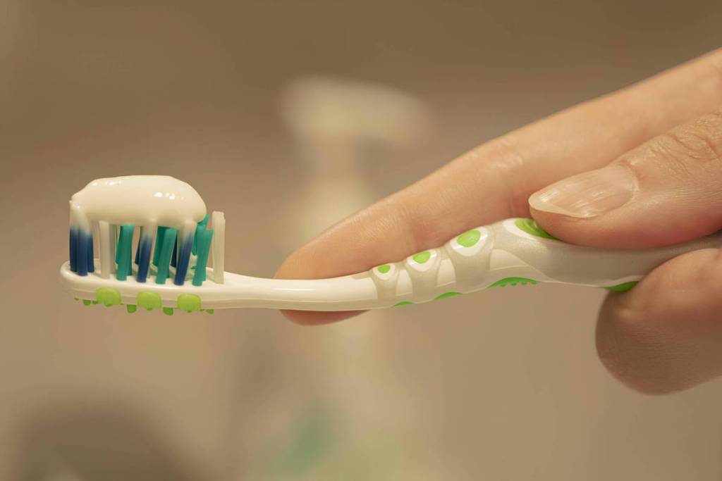 A person holding a toothbrush with toothpaste on it