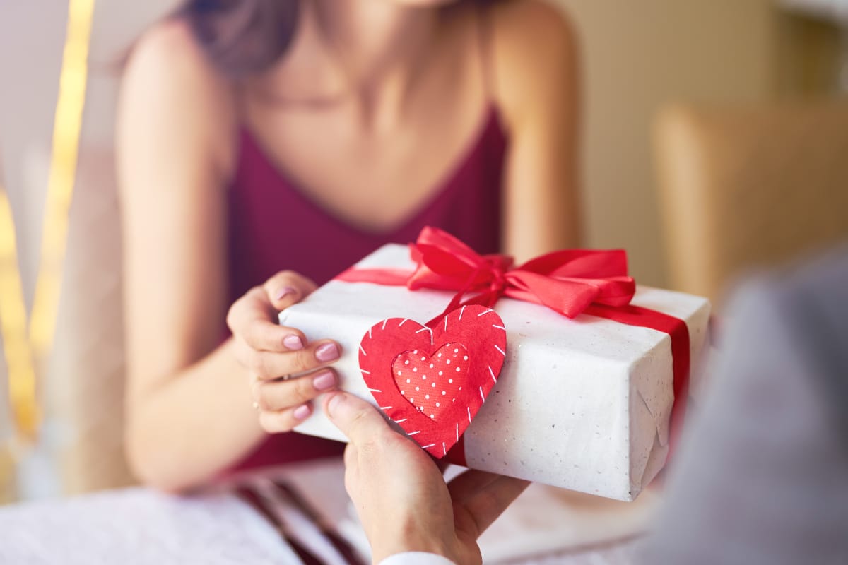 Frau überreicht ein Geschenk zum Valentinstag