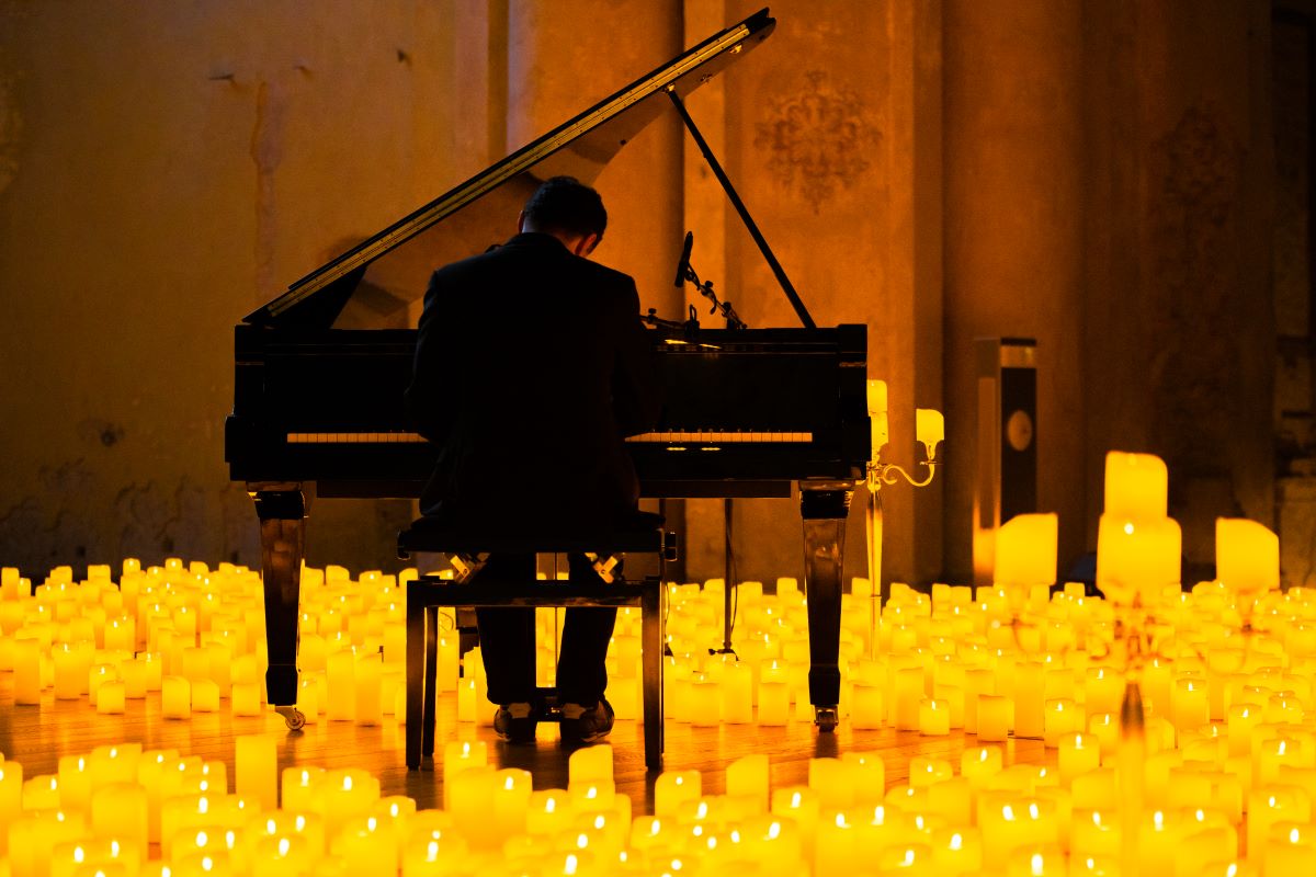Pianist spielt bei einem Candlelight-Konzert auf einem Flügel, umringt von etlichen Kerzen