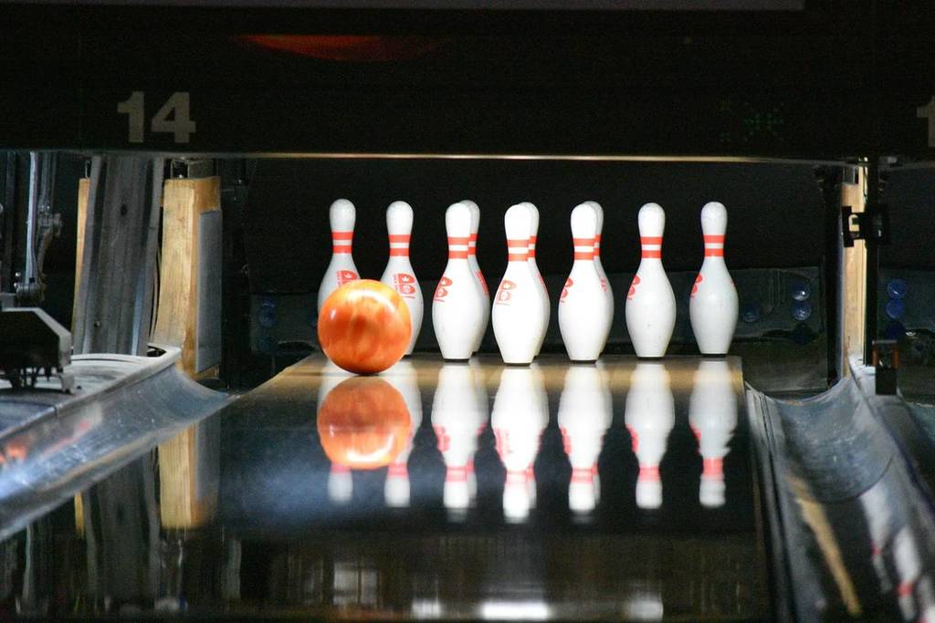 The ball rolls toward the bowling pins