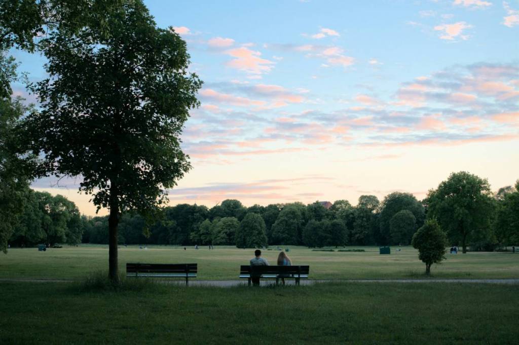 leute sitzen auf einer bank im englischen garten