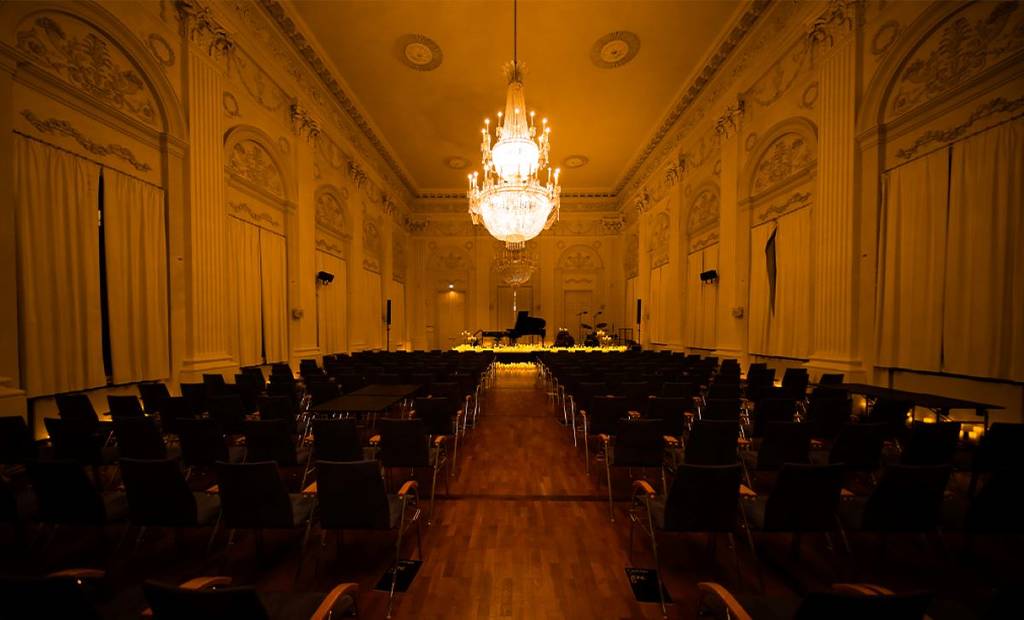 Candlelight concert in the Max-Joseph-Saal in Munich, instruments on stage between a sea of candles, empty rows of seats in the foreground
