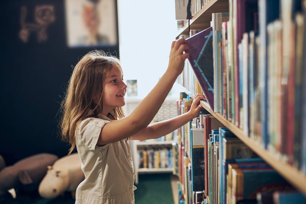 girl takes book from shelf