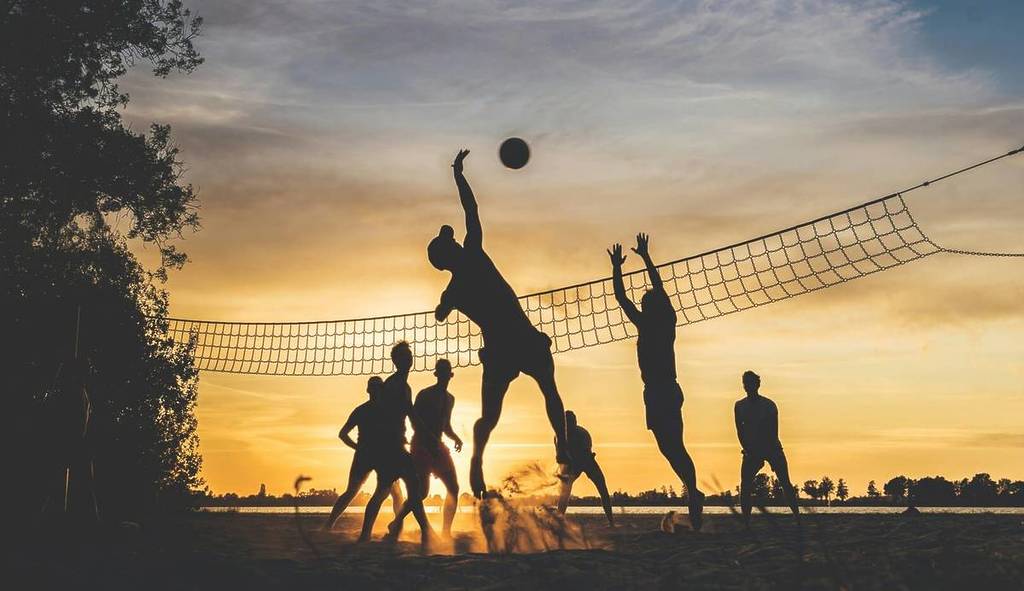 personen spielen volleyball im sonnenuntergang