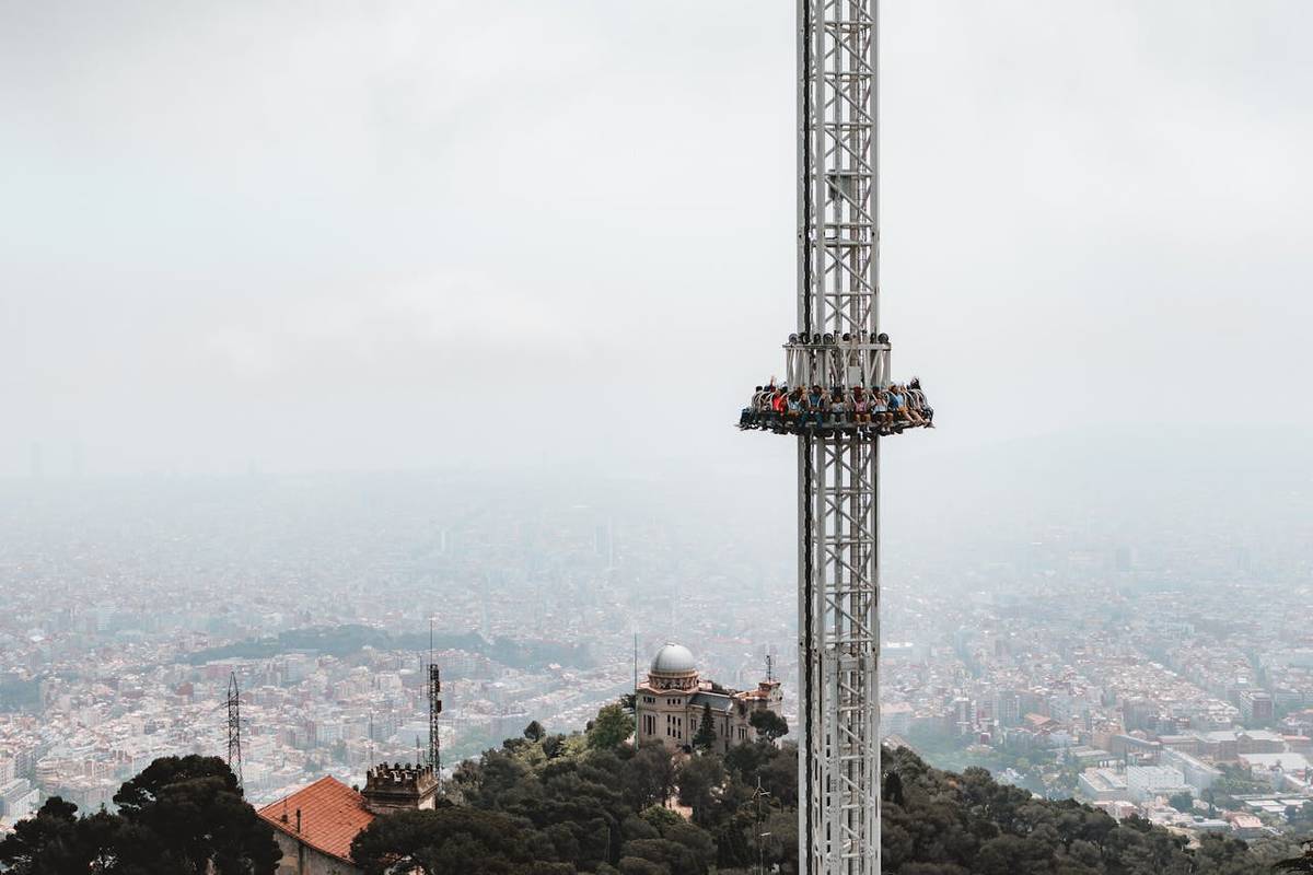 mitfahrende in einem drop tower bei nebliger landschaft