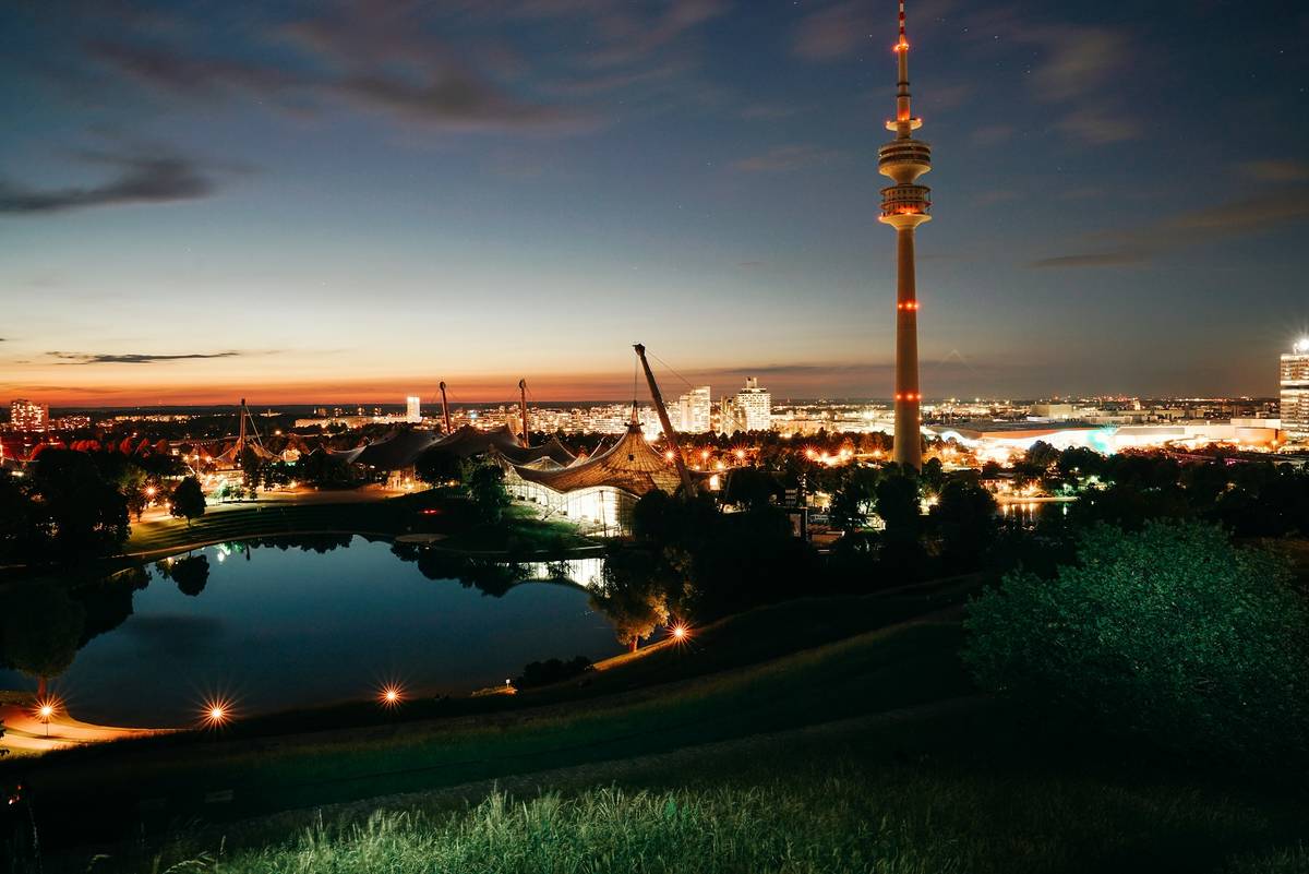 olympiapark in der nacht mit beleuchteter stadt im hintergrund
