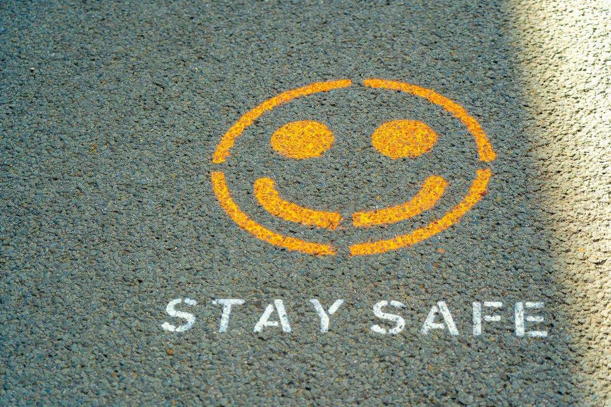 aufgemalter smiley auf asphalt mit der schrift stay safe darunter
