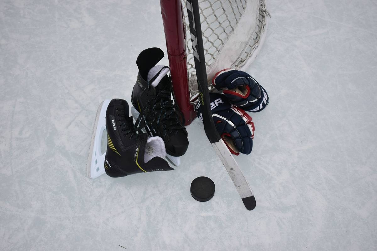 schlittschuhe, puck, schläger und anderes eishockey equipment auf dem eis neben eine tor
