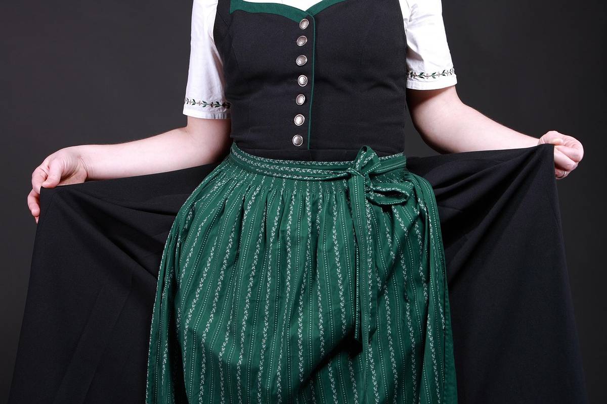 frau mit schwarzem dirndl und dunkelgrüner schürze