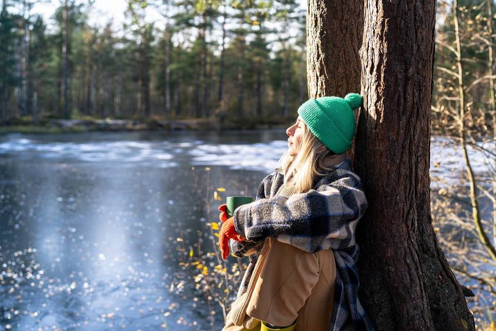 Woman in winter clothing looking at a frozen lake