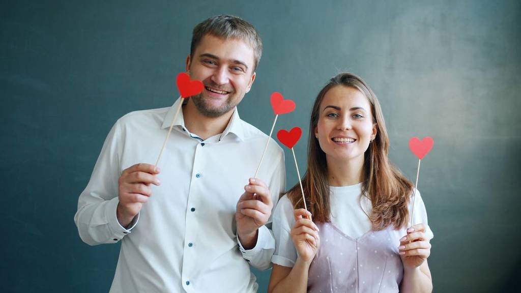women and men hold up hearts, May Day dance singles party
