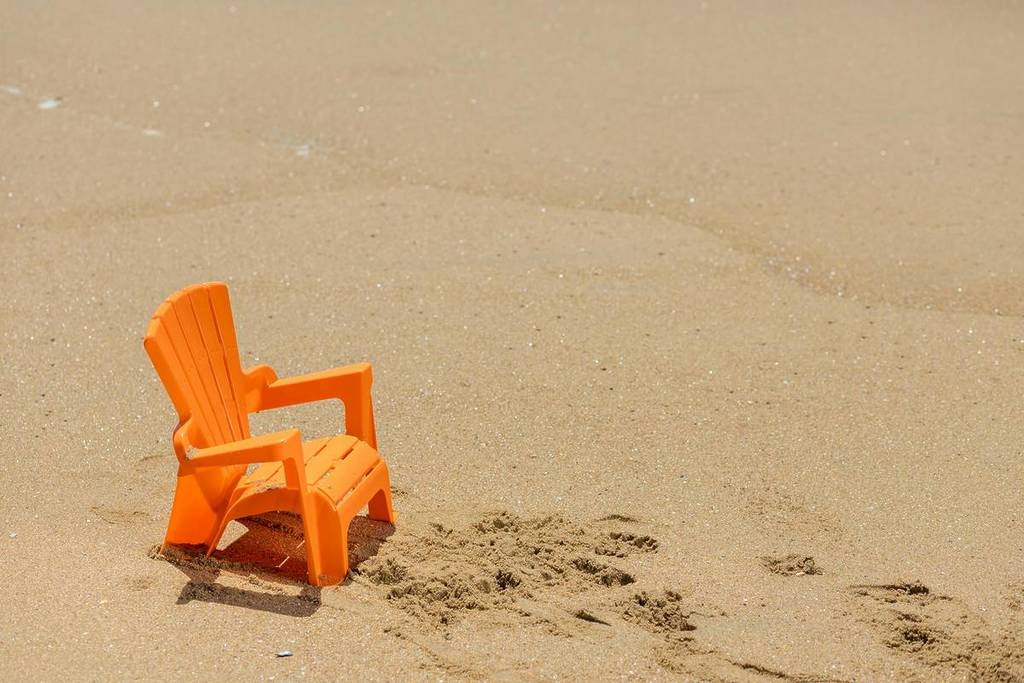 kleiner oranger stuhl im sand