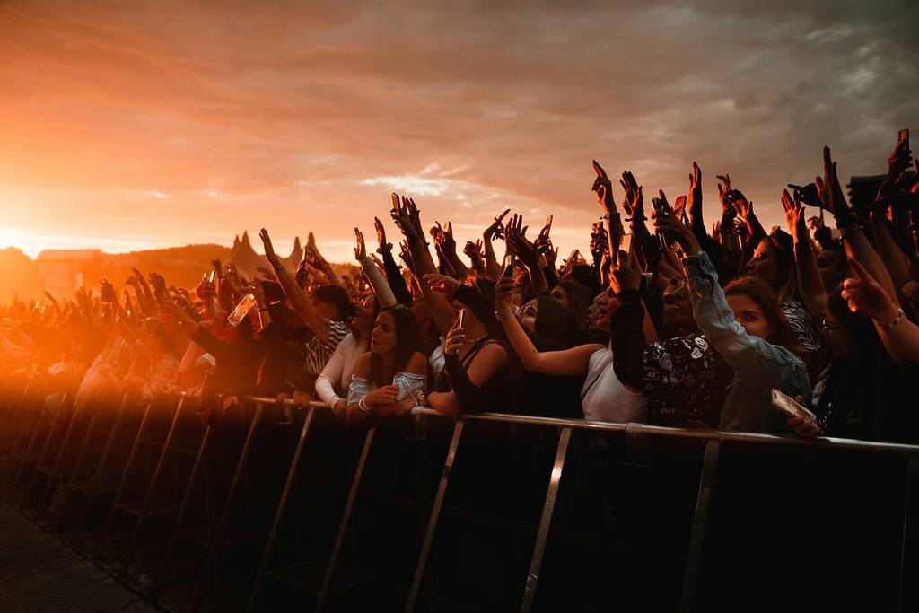people behind a barrier celebrating at sunset