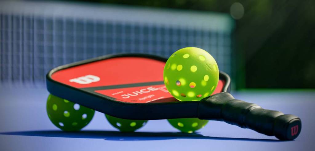 pickleball paddles and balls in front of the net