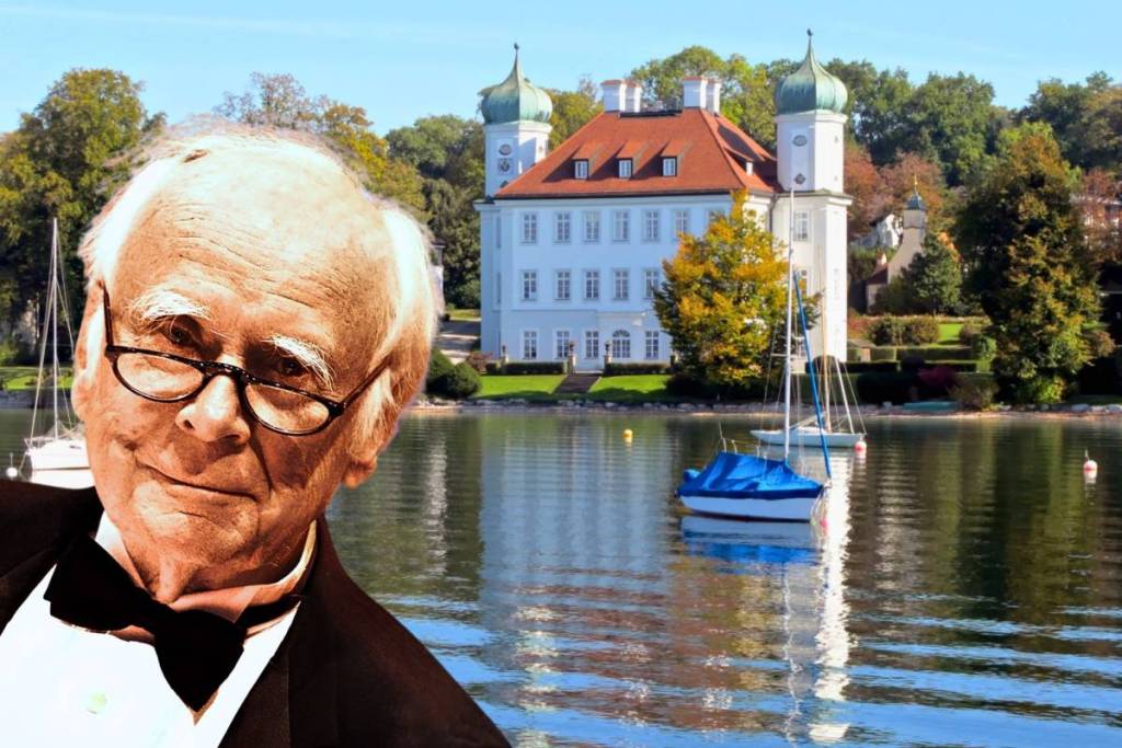 Portrait of comedian Loriot in front of the historic Ammerland Castle and sailboats on Lake Starnberg.