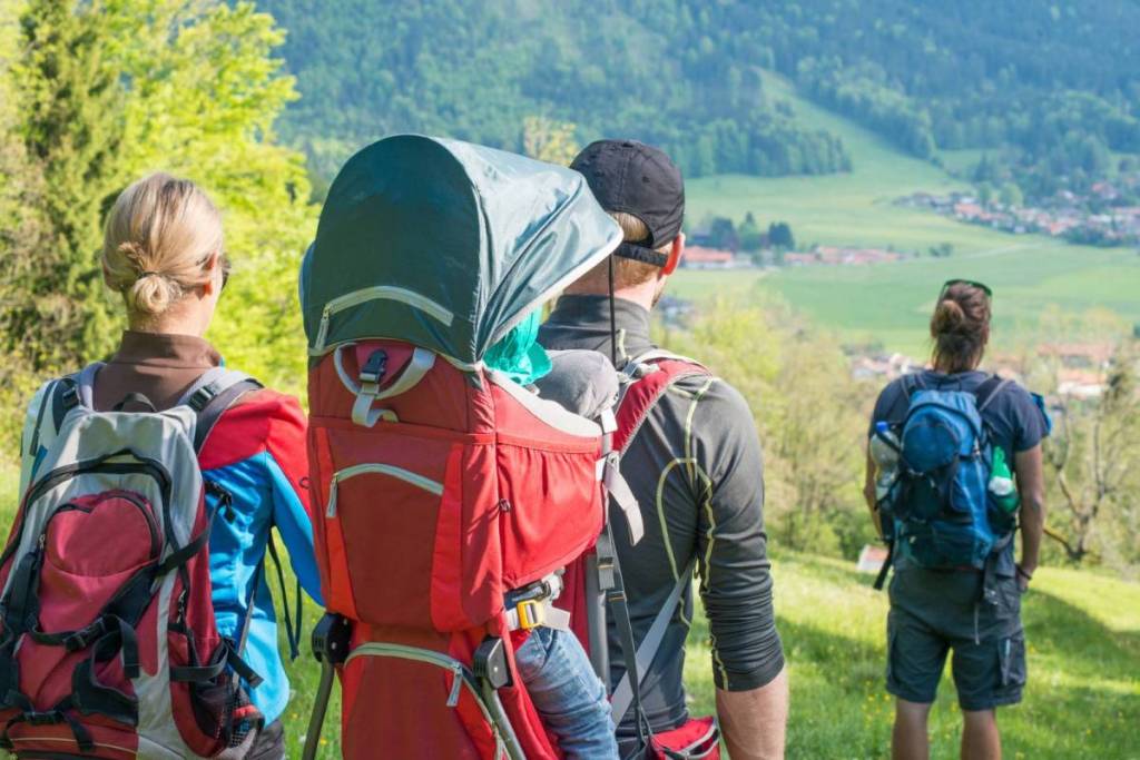 Personen mit Wanderrucksäcken schauen in ein Tal hinein