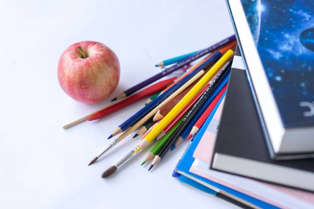 bücher, stifte und ein apfel auf dem tisch