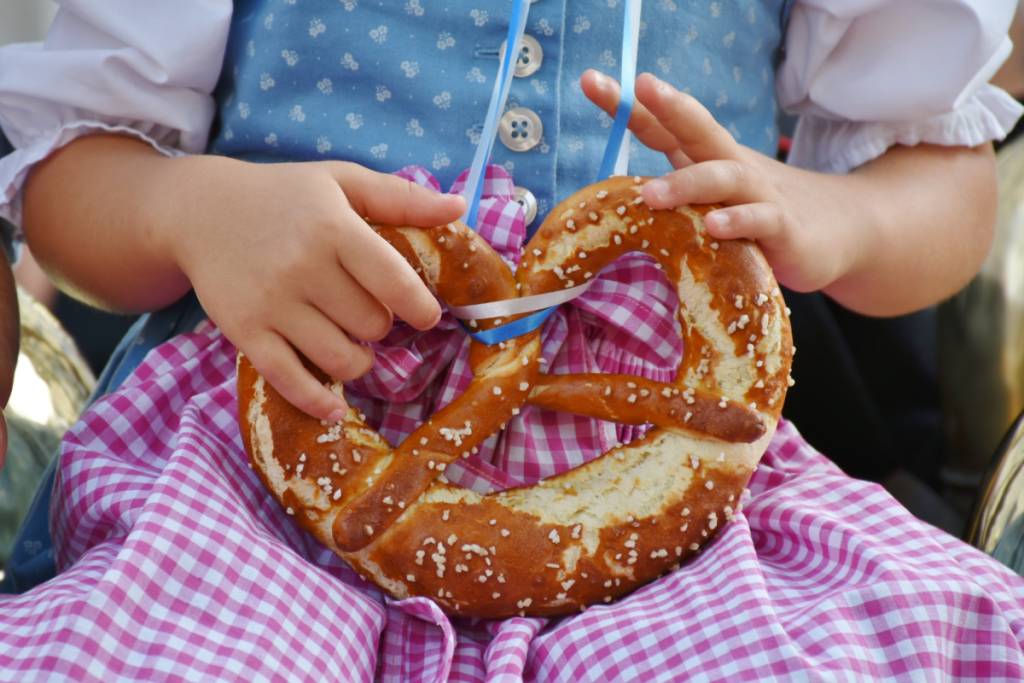 Nahaufnahme einer Breze, die von einem Kind in Tracht gegessen wird