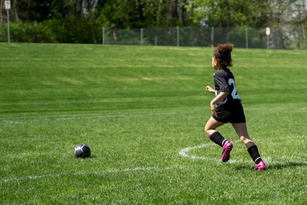 Mädchen spielt Fußball auf einer Wiese