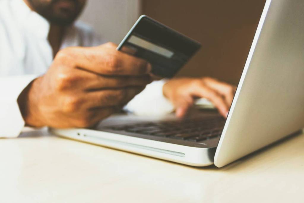 person with a credit card in front of a laptop
