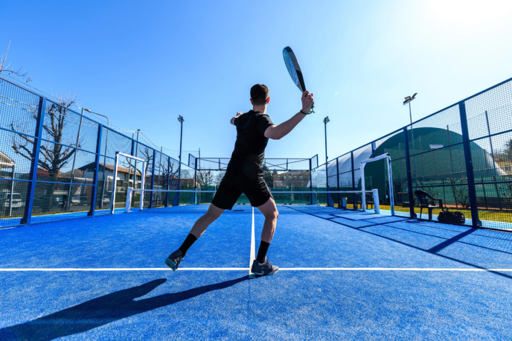 A man plays padel on a blue court