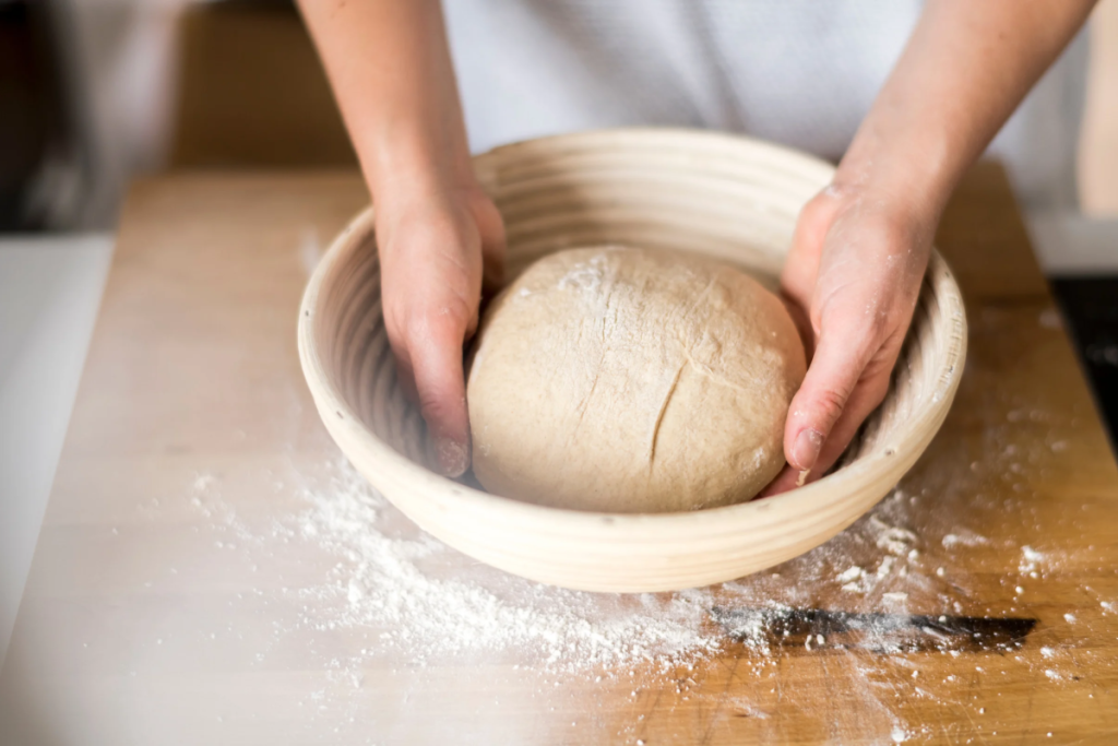 A person places dough into a basket