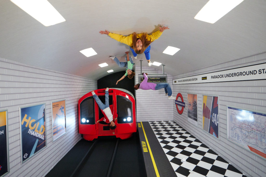 A family has fun with optical illusions in a set designed like a train station at the Paradox Museum.