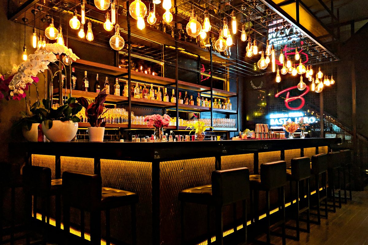 A bar full of spirits and illuminated by hanging light bulbs