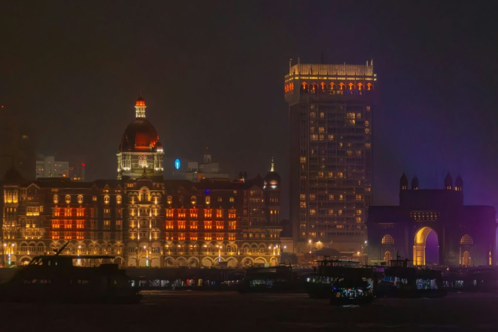 A landscape image of some of Mumbai's most iconic landmarks at night including the Gateway of India