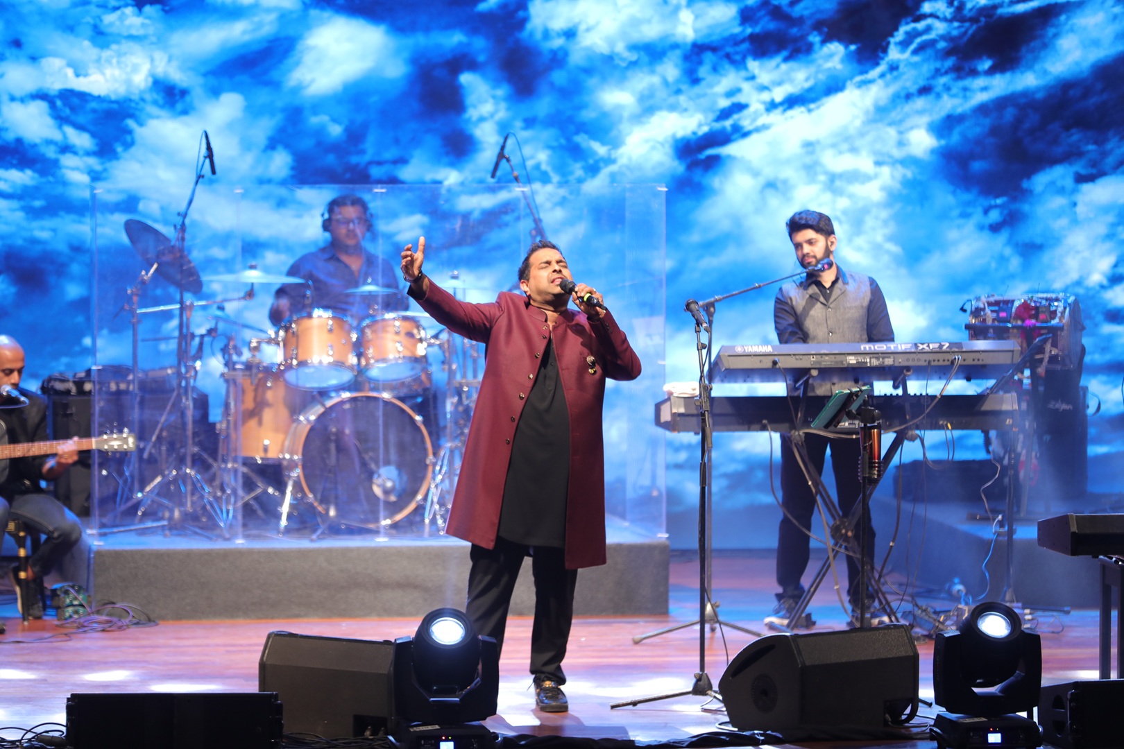 The members of Shankar–Ehsaan–Loy perform on stage, lit by a blue swirling background.