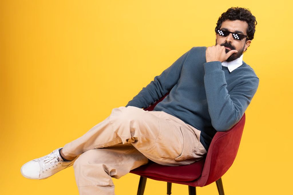 Azeem Banatwalla - sat posed on a chair with pixelated sunglasses