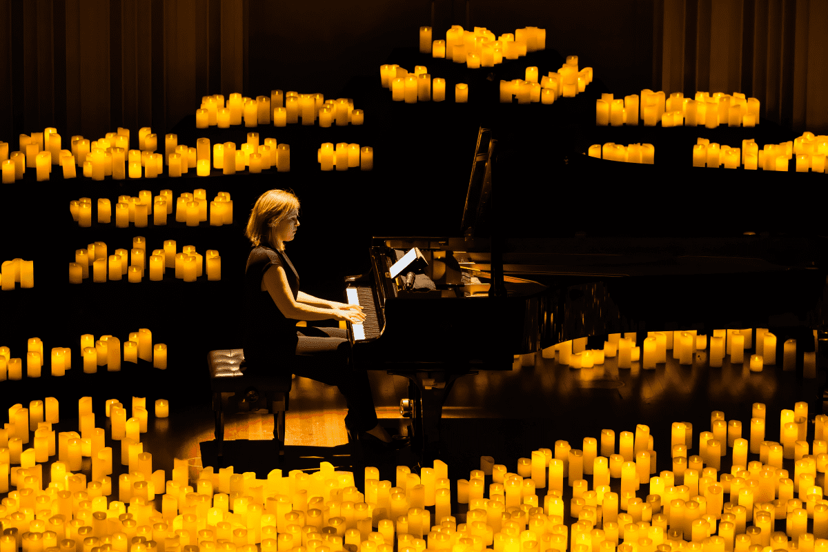 A pianist performing on a stage illuminated by a sea of candles
