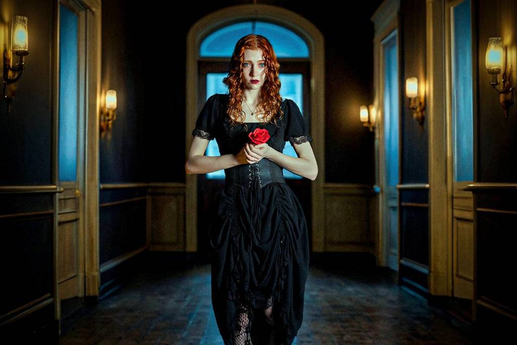 woman in dimly lit hall holding a rose