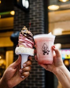 Hand holding ice cream and another hand holding a slushie