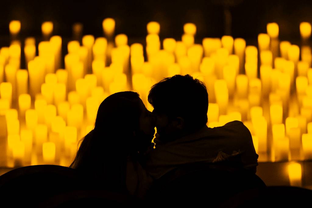The silhouette of a couple kissing in front of a sea of candles