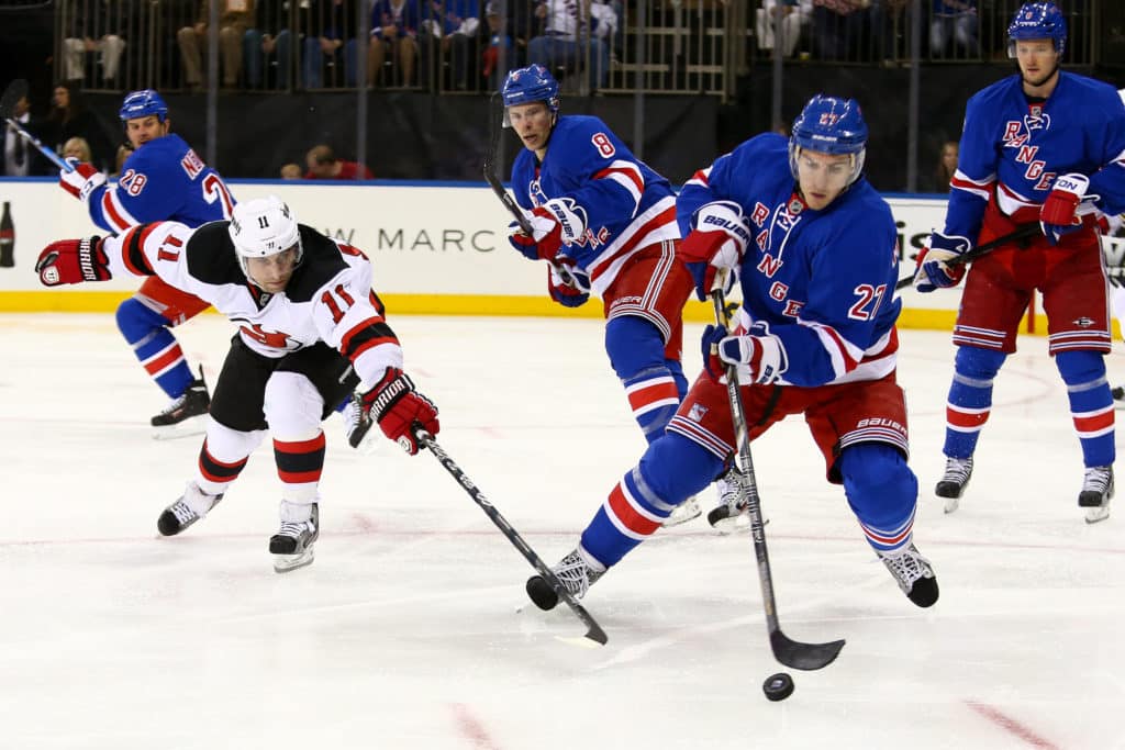NUEVA YORK, 27 DE ABRIL: El defensa de los New York Rangers, Ryan McDonagh (27), y el extremo derecho de los New Jersey Devils, Stephen Gionta (11), luchan por el disco en el Madison Square Garden el 27 de abril de 2013 en la ciudad de Nueva York.