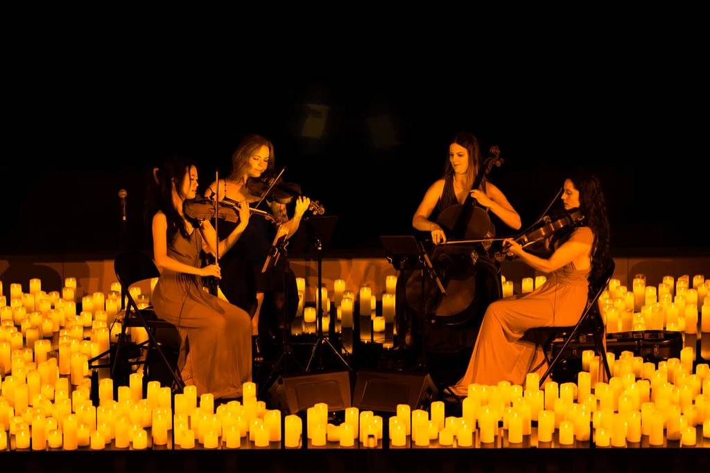 A string quartet performing amid a sea of candles