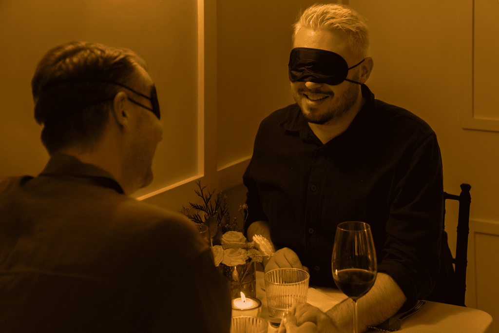 A blindfolded couple holding hands at Dining in the Dark