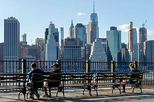 People sitting on benches in Brooklyn Heights with the Manhattan skyline