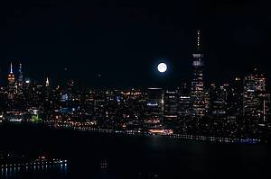 Scenic Aerial New York City Night View of Manhattan Architecture and Big Shining Full Moon. Panoramic Financial District Photo from a Helicopter. Cityscape with Office Buildings and Skyscrapers