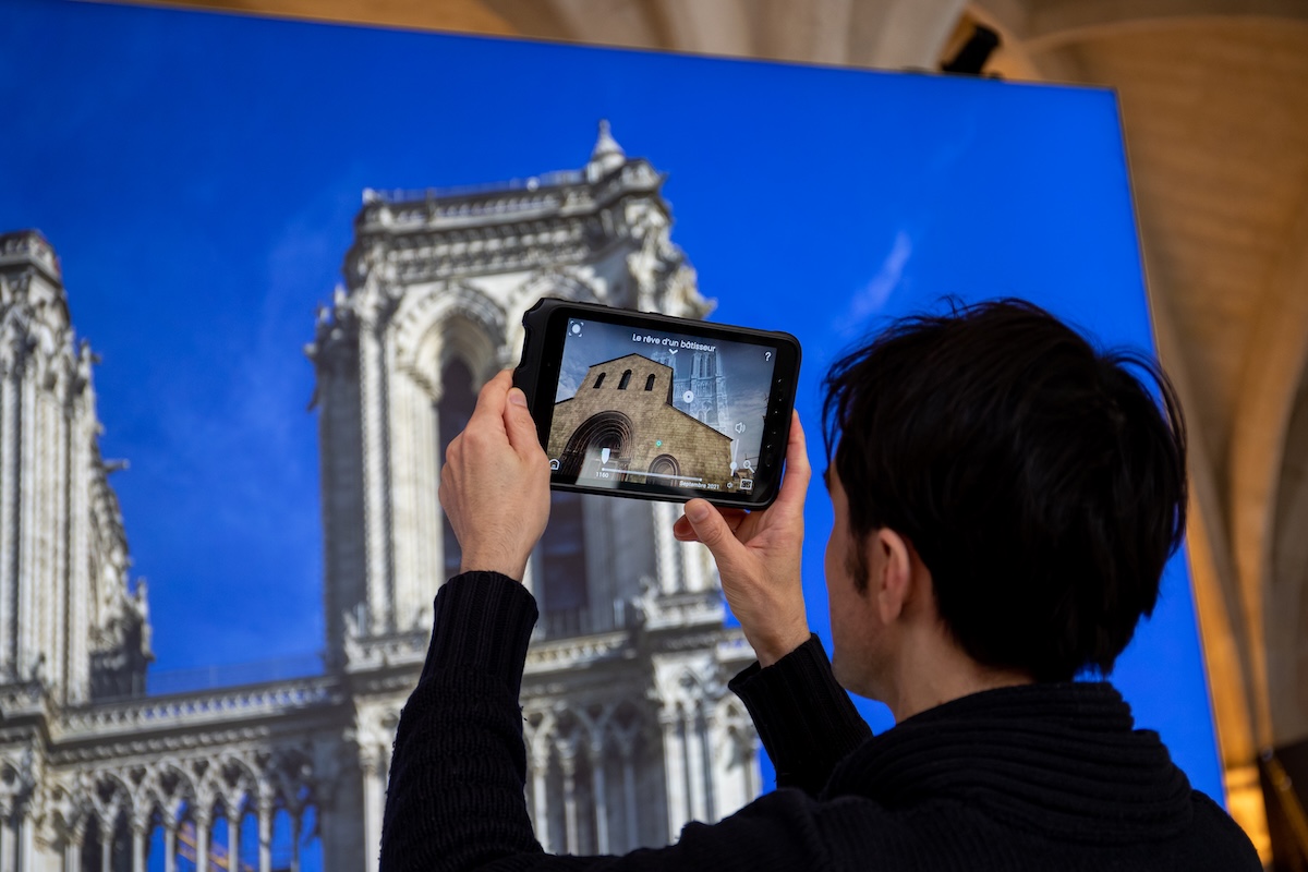 A person taking a photo of a photo of the Notre-Dame in Notre-Dame de Paris: The Augmented Exhibition