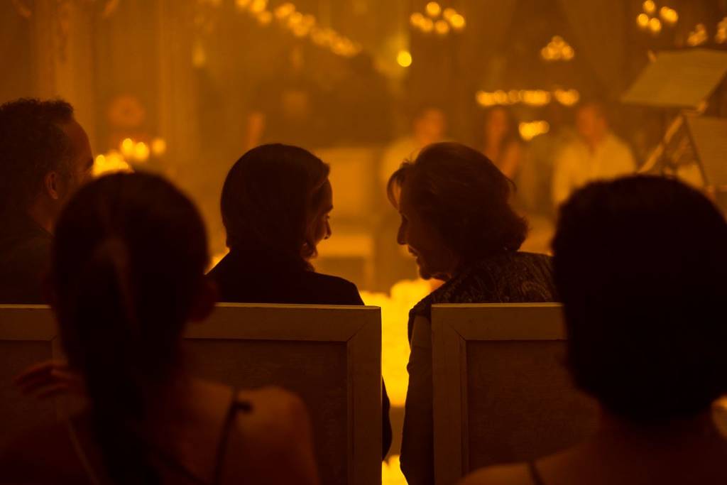 The silhouettes of two women leaning over to discuss a Candlelight concert