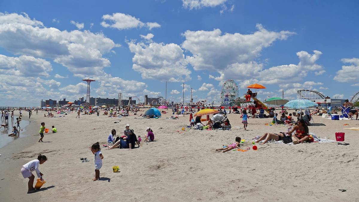 New York, US - June 30. 2016: Coney Island beach with families and the famous Luna Park in the background