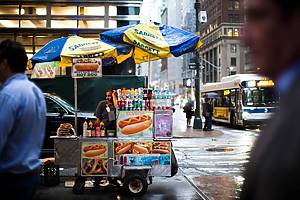 New Yorkers walking past a food cart
